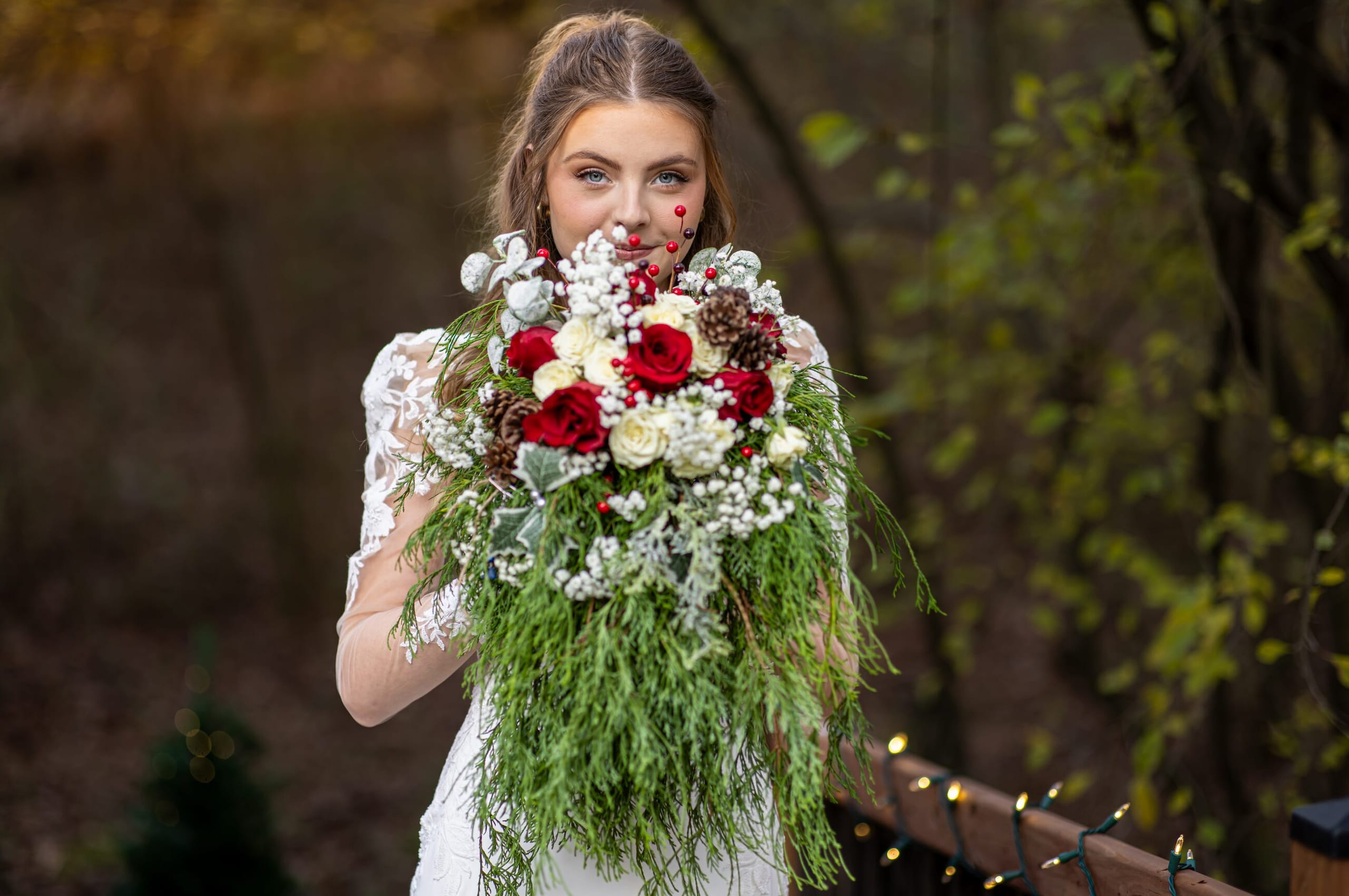 Bride holding a winter bouquet of red roses and cedar